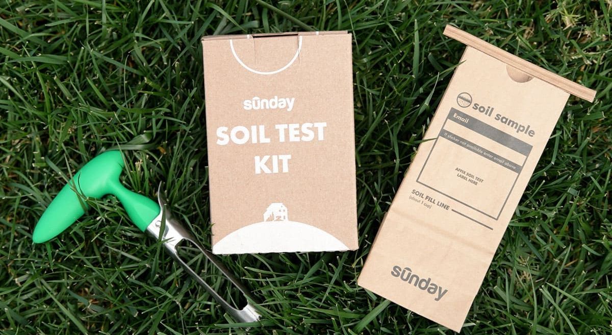 Sunday Soil Test Kit shipping box, collection bag, and a green soil corer on the grass, ready to reveal the truth under the yard.
