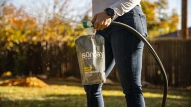 Person applying fall lawn fertilizer to lawn
