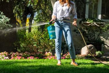 Woman applying Sunday lawn fertilizer with Sunday's custom-engineered lawn sprayer