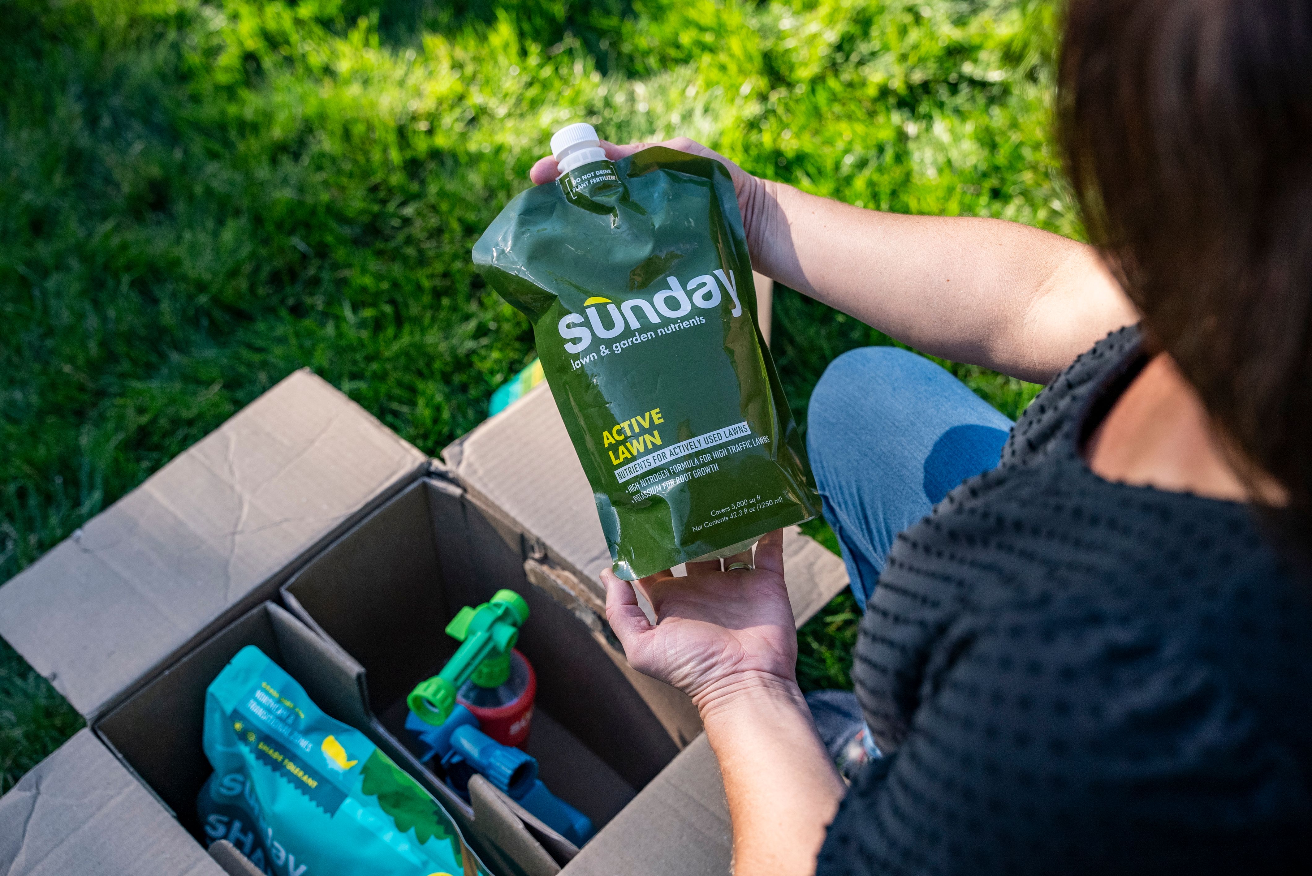 Woman unboxing a Sunday custom lawn plan