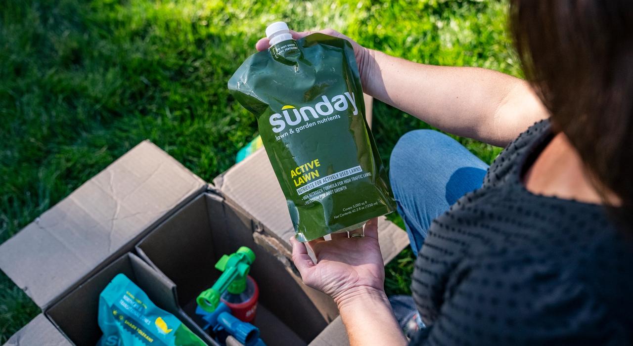 Woman unboxing a Sunday custom lawn plan