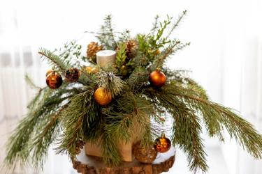 A display of pine tree branches and ornaments in a vase.