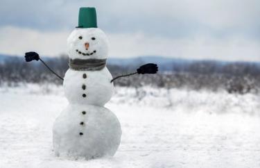 Winter snowman with a top hat, mittens, scarf and six buttons in an open field.