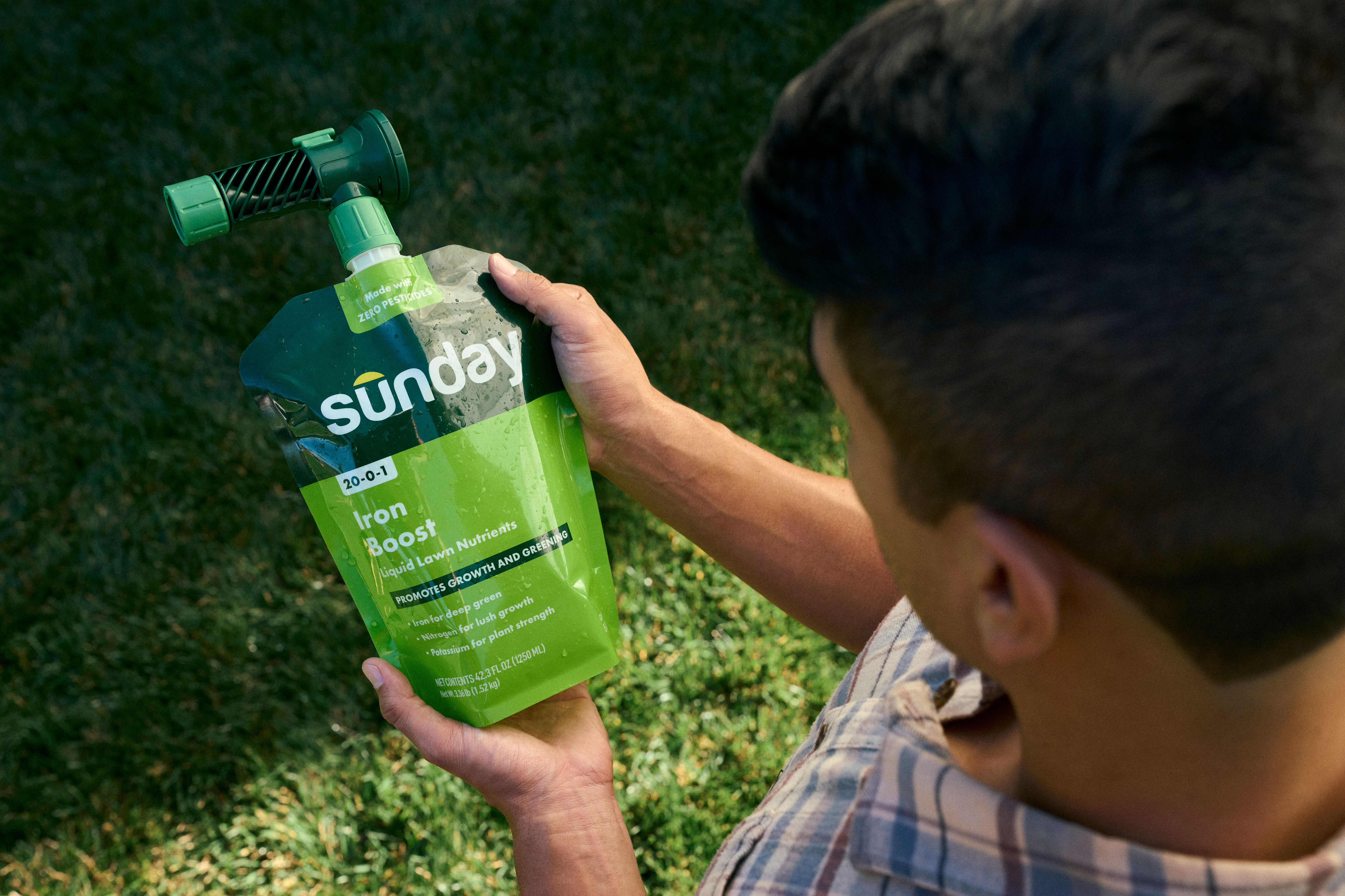 Person looking at a pouch of liquid fertilizer with hose end sprayer attached