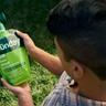 Person looking at a pouch of liquid fertilizer with hose end sprayer attached