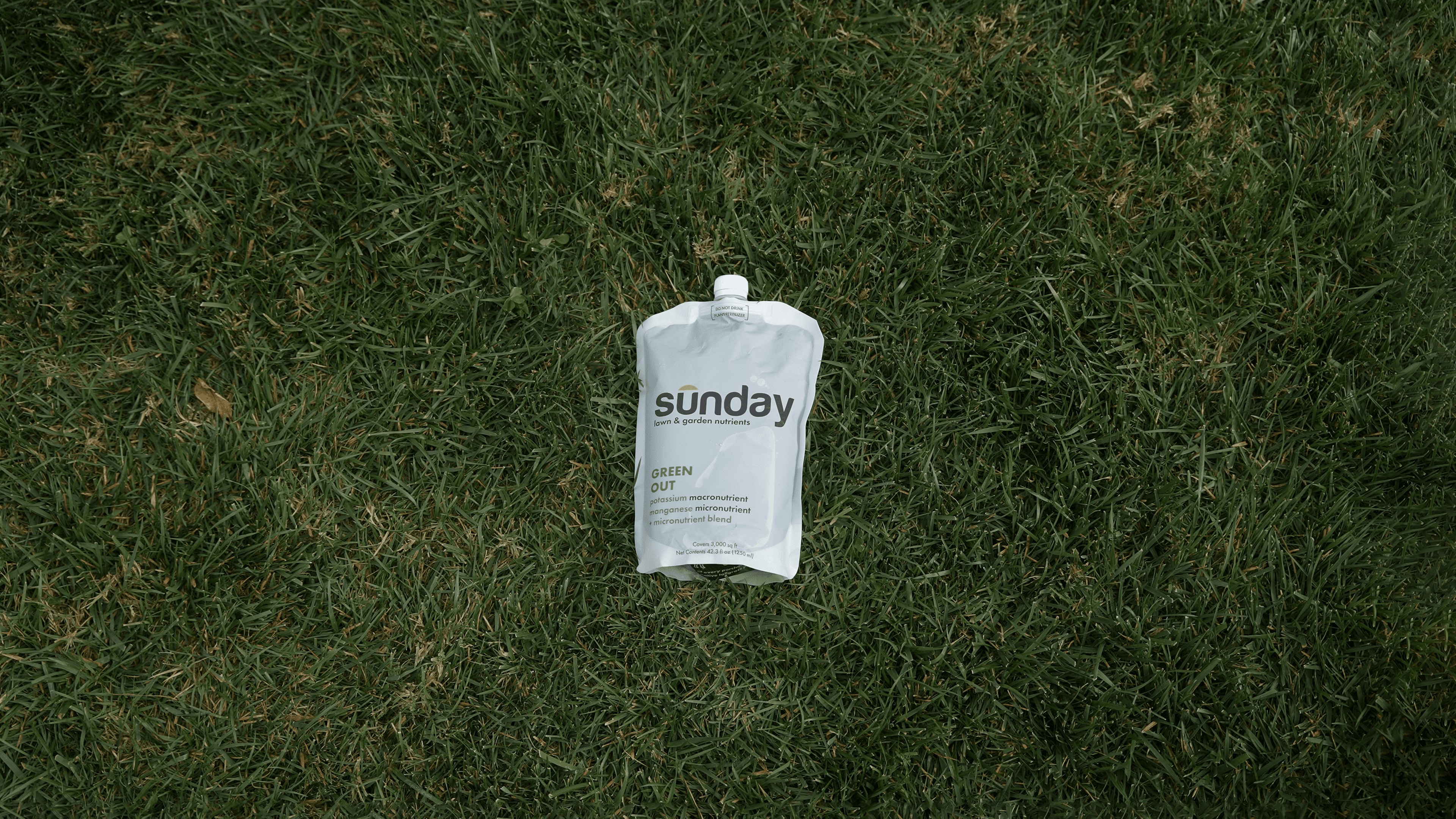 Green Out liquid lawn fertilizer pouch on lawn