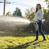 Person applying fall lawn fertilizer on green fall lawn