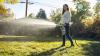 Person applying fall lawn fertilizer on backyard lawn