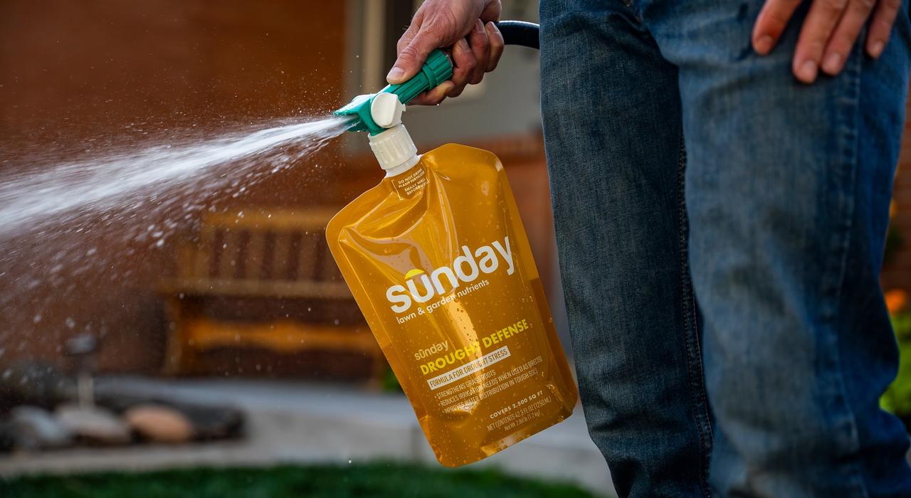Man applying Sunday Drought Defense lawn treatment on lawn