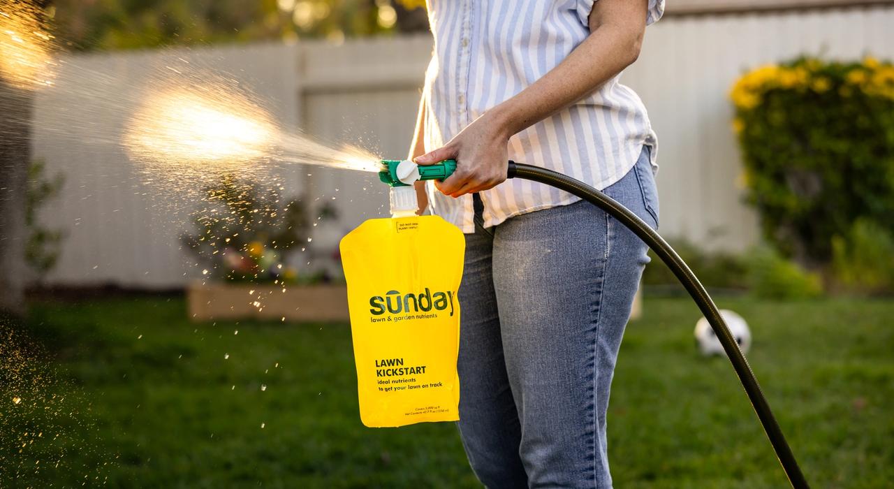 A woman sprays Sunday Lawn Kickstart
