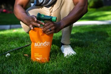 Man securely attaching Sunday sprayer to fertilizer pouch