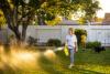 Woman watering grass with Sunday lawn nutrients