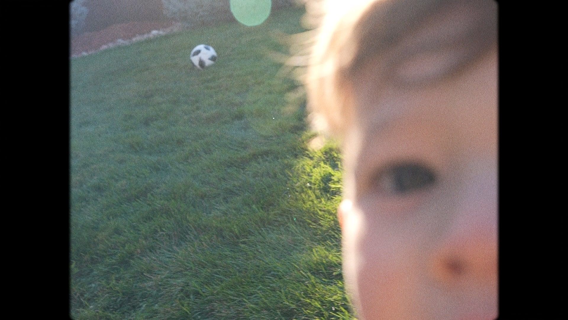 Close up of baby and soccer ball on a green Sunday lawn