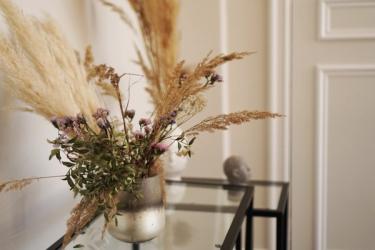 A bouquet of dried blooms in a vase on an entry table.