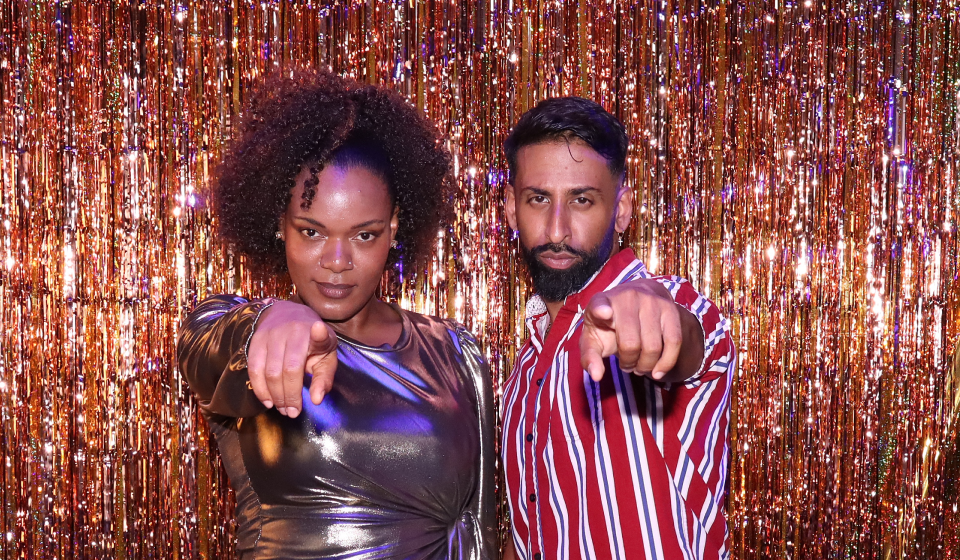 Two people at a photo booth pointing to the camera.