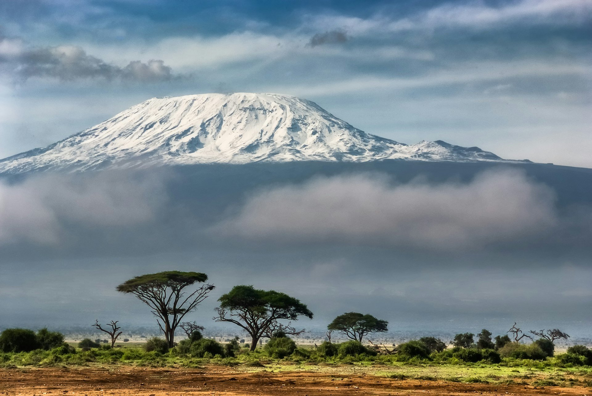 Snow-capped Mount Kenya peak above the clouds at golden hour