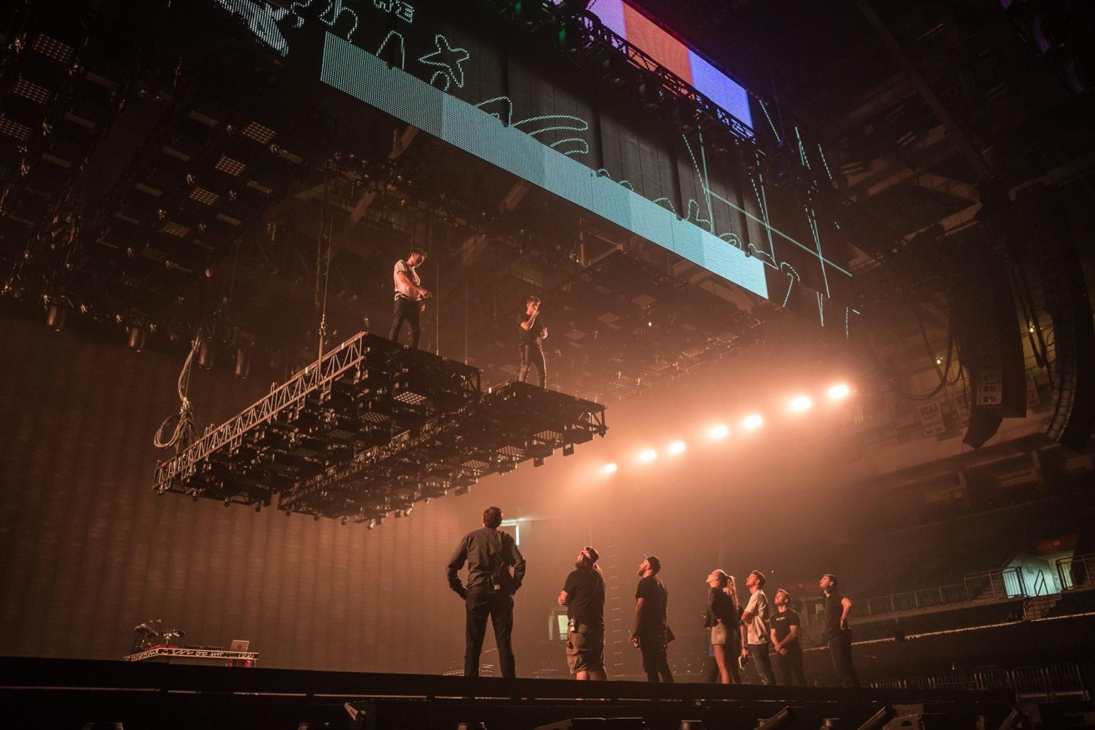 Do Not Open design and tour crews look up at Alex and Drew of The Chainsmokers as they test out risers for their upcoming concert tour.