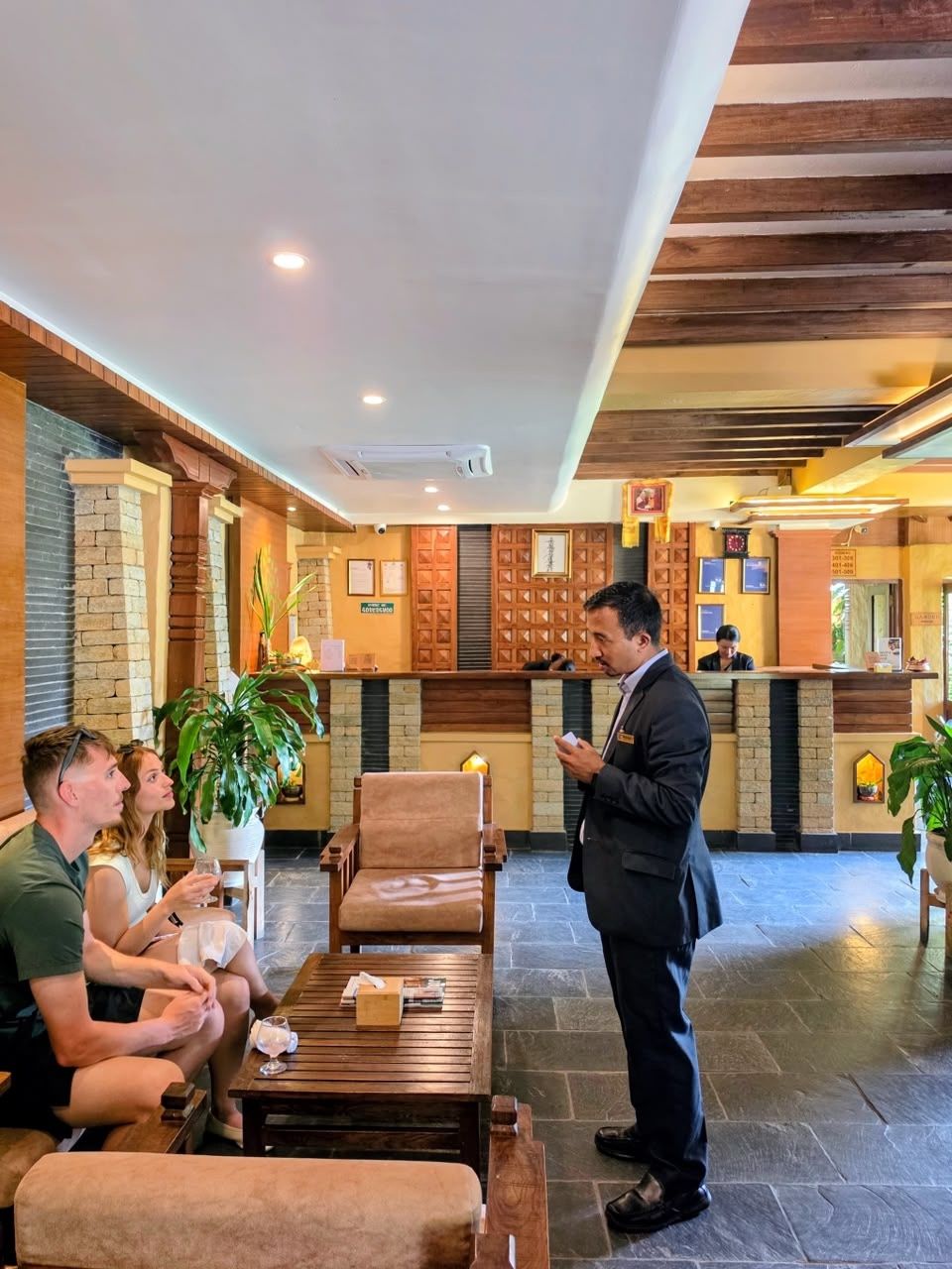 A member of the team talking with guests in the lobby, the front desk behind