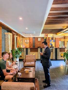 A member of the team talking with guests in the lobby, the front desk behind