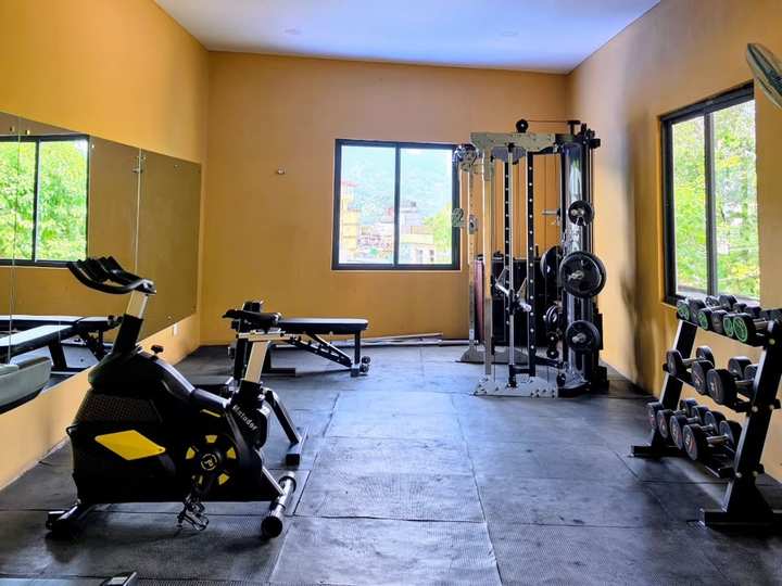 The fitness centre: a spin bike, benches, a cable machine and a rack of dumbbells