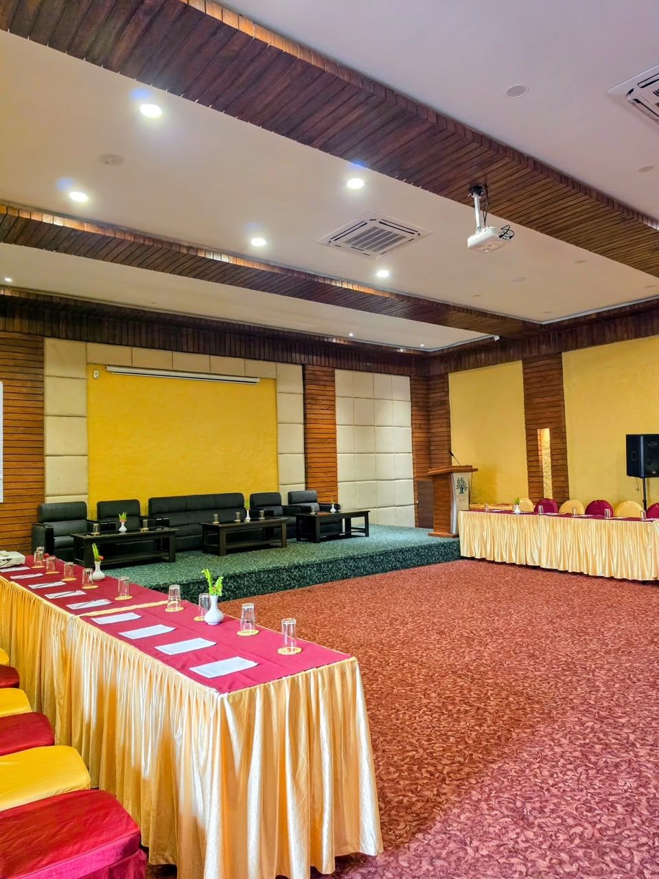The hall set for a meeting: a stage with sofas, a lectern and tables in a U