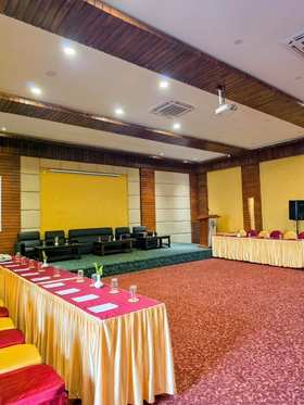 The hall set for a meeting: a stage with sofas, a lectern and tables in a U