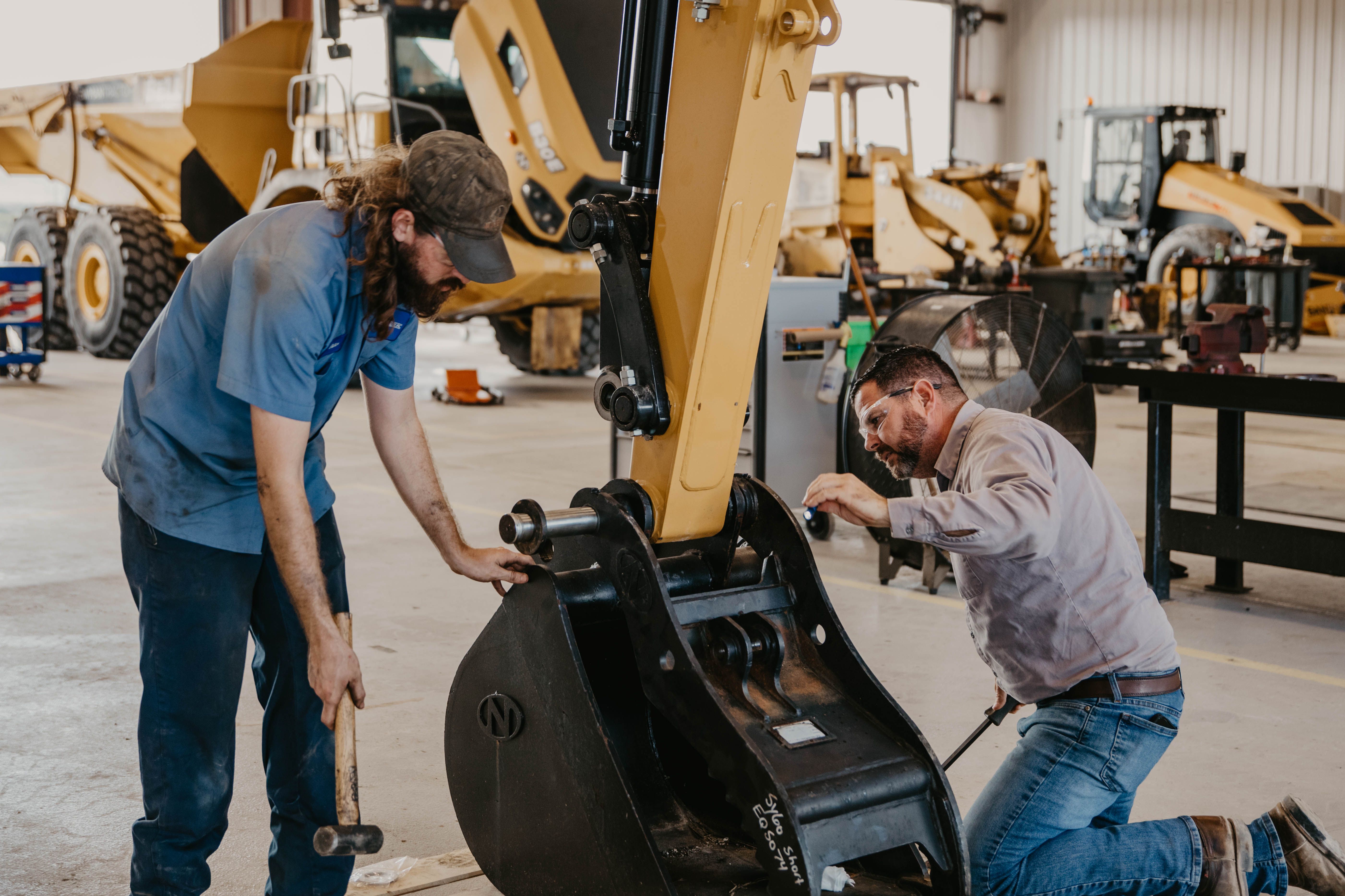 two men working on an excavator bucket
