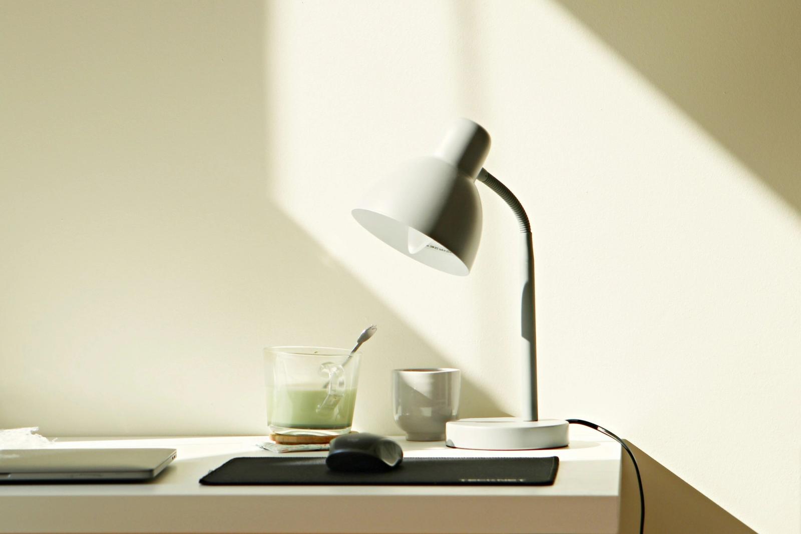 Bureau blanc avec une tasse, une souris et une lampe