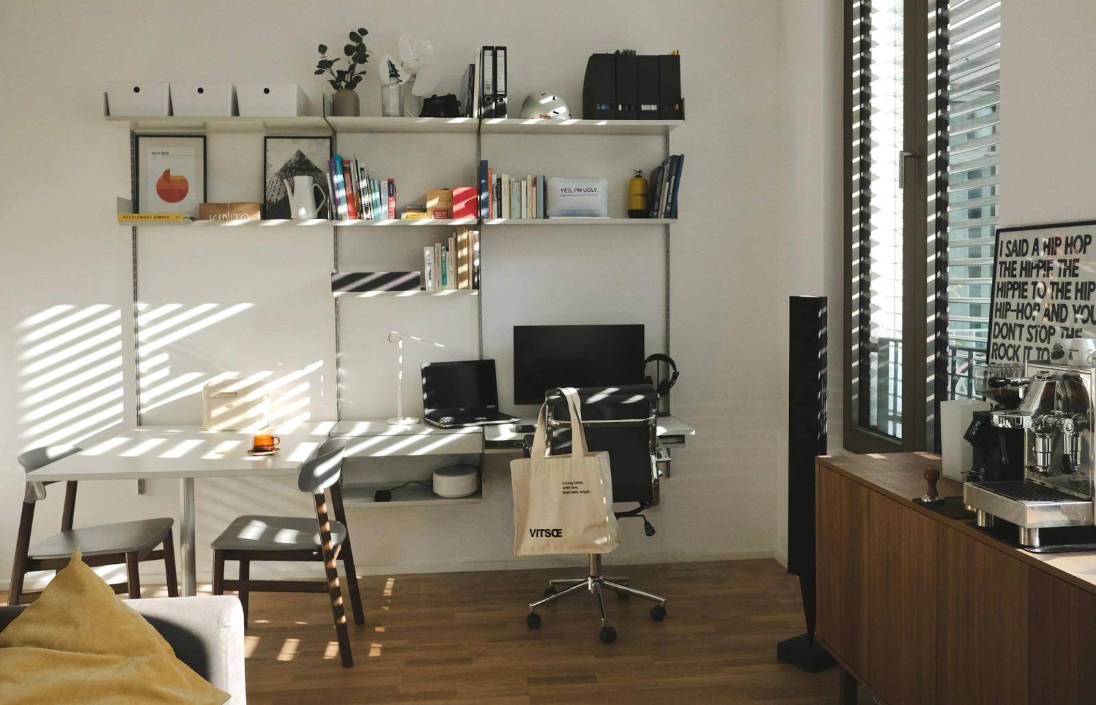 Espace de travail propre et sobre, avec un bureau organisé, une machine à expresso et un canapé.