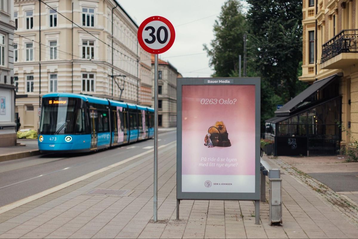 Plakat for Sem & Johnsens Postkodehunder på Frogner plass, med trikk bak