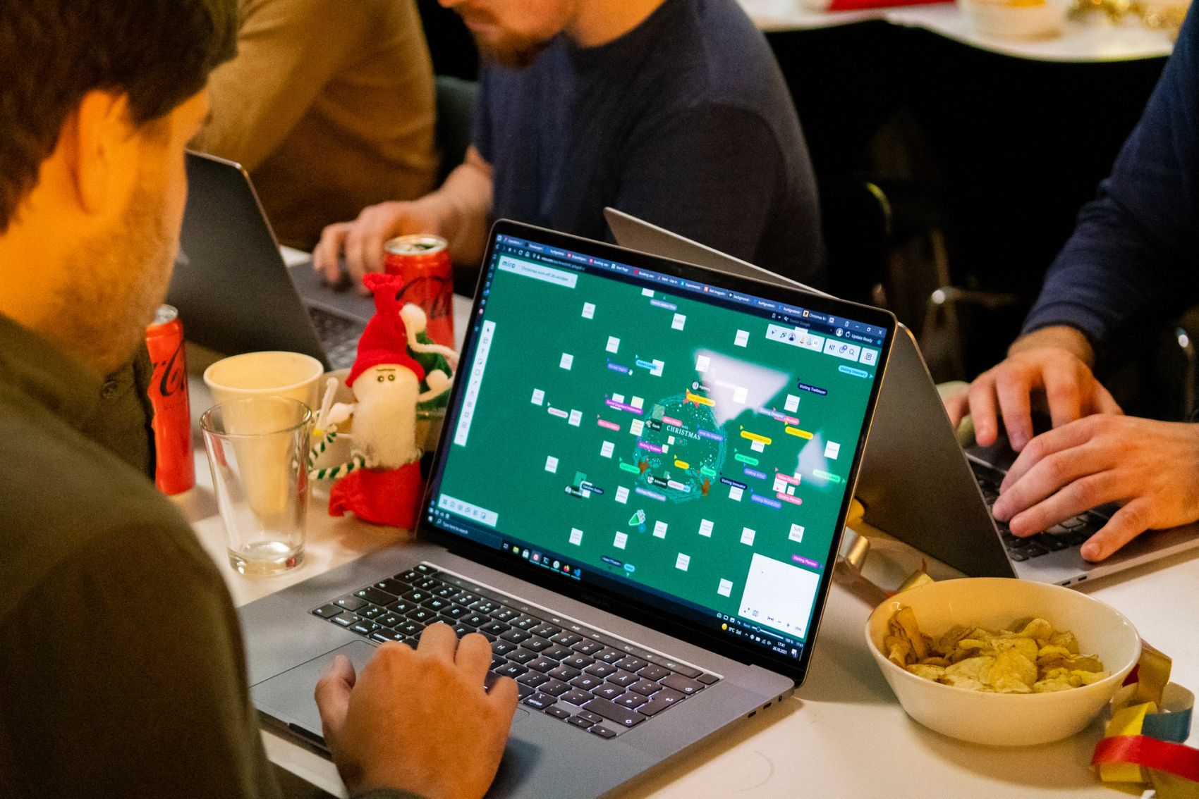 A man looking at a miro board on his computer, with tons of ideas and people interacting