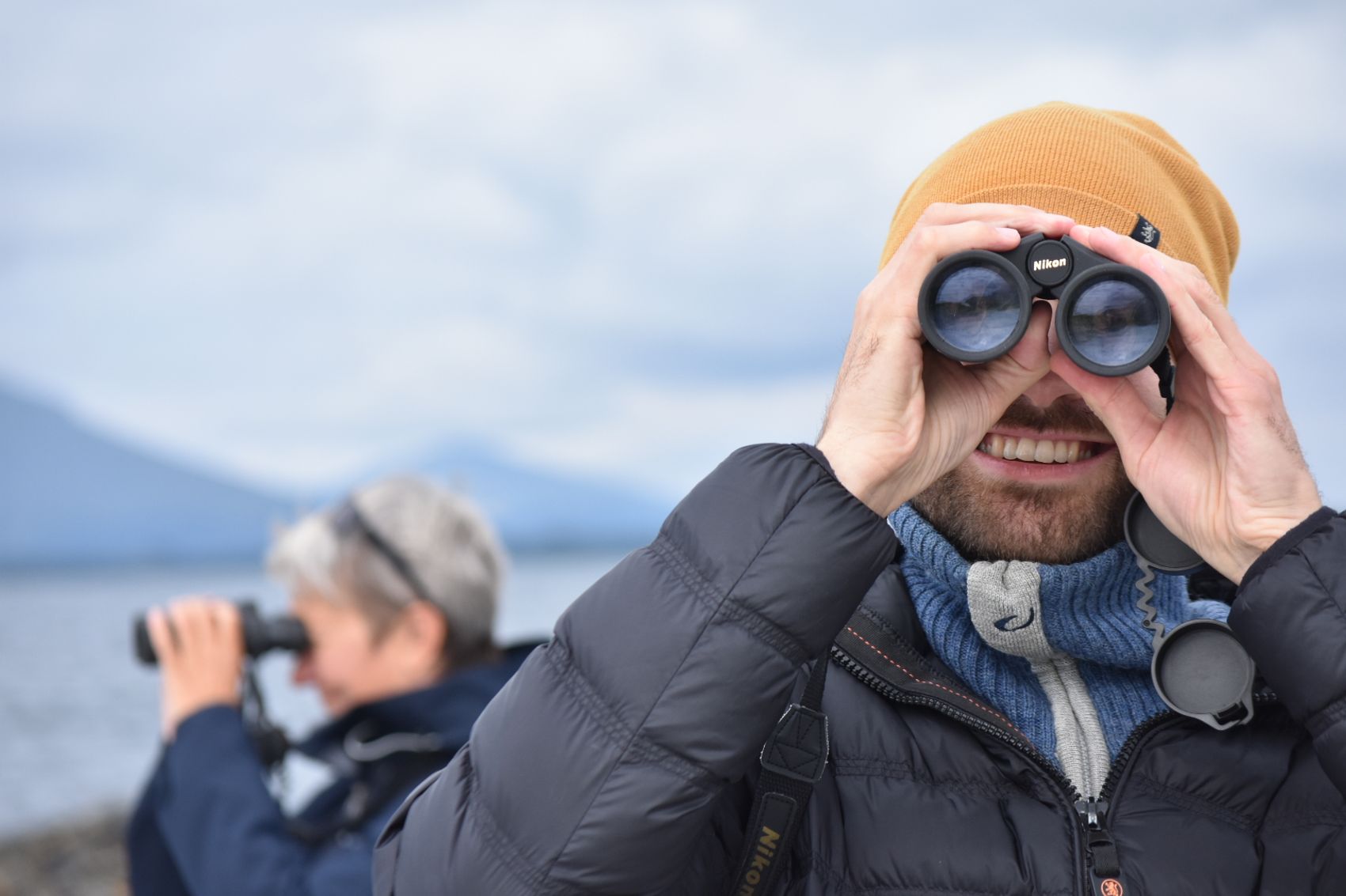 Bilde av meg som ser direkte inn i kamera med kikkert, med et digert glis om munnen