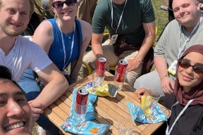 6 glade konferansedeltakere smiler til kameraet utendørs i sola