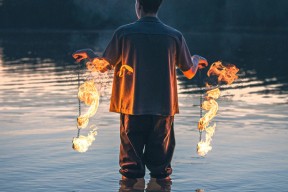 En mann som står i vannet med to brennende lenker