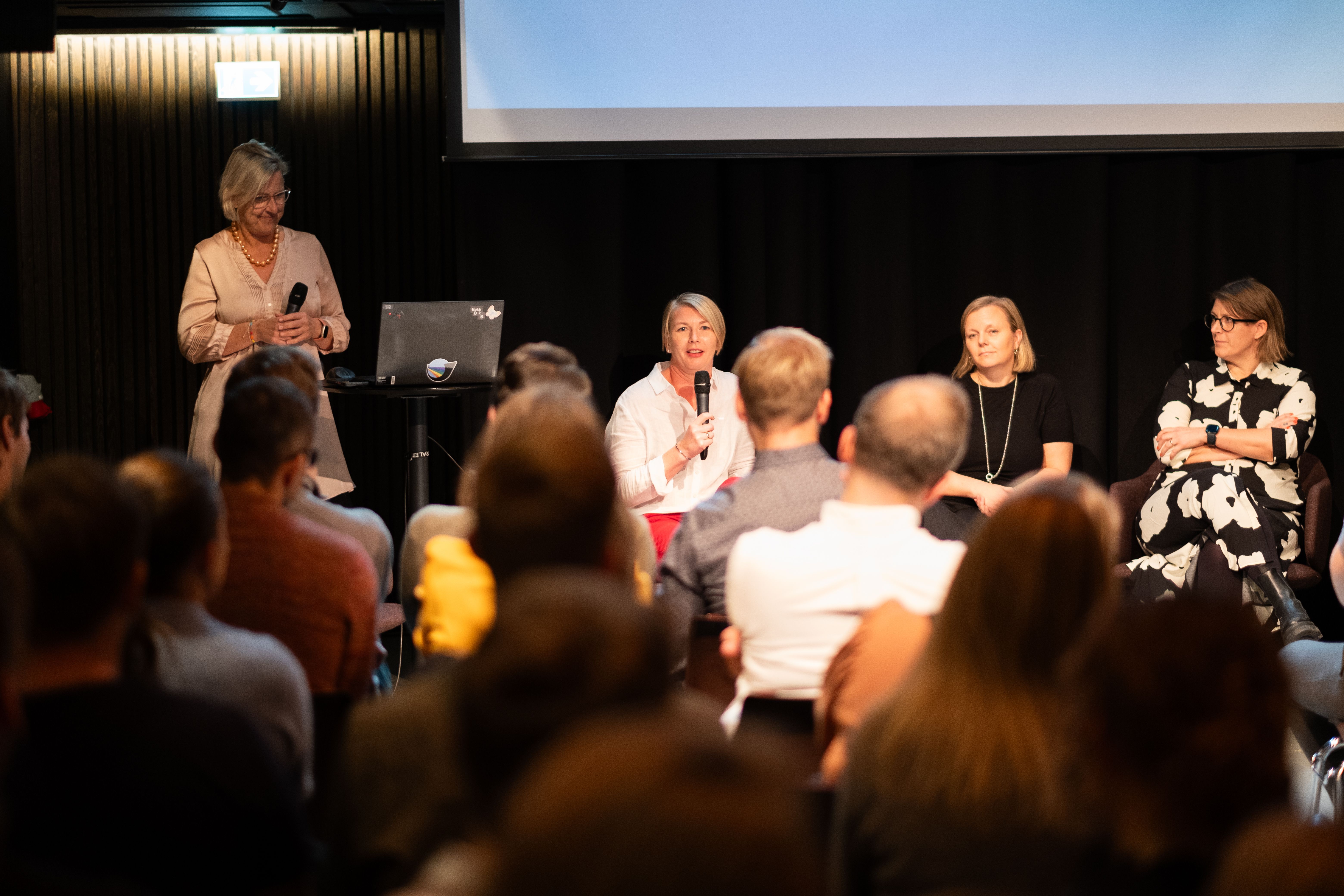 Bilde av Kjersti som presenterer sammen med tre andre kollegaer foran en fullsatt sal.