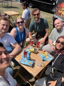 6 glade konferansedeltakere smiler til kameraet utendørs i sola