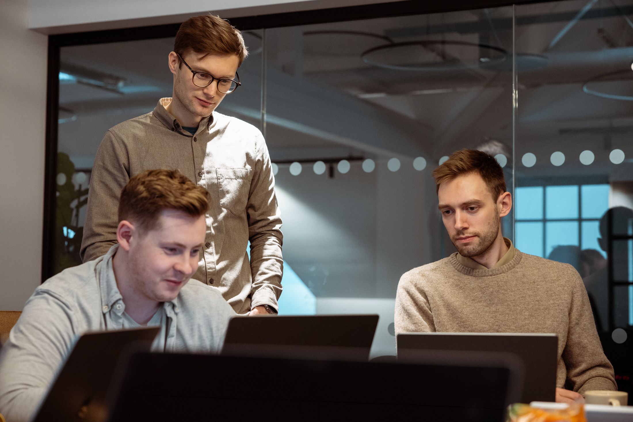 Tre menn som ser på pc