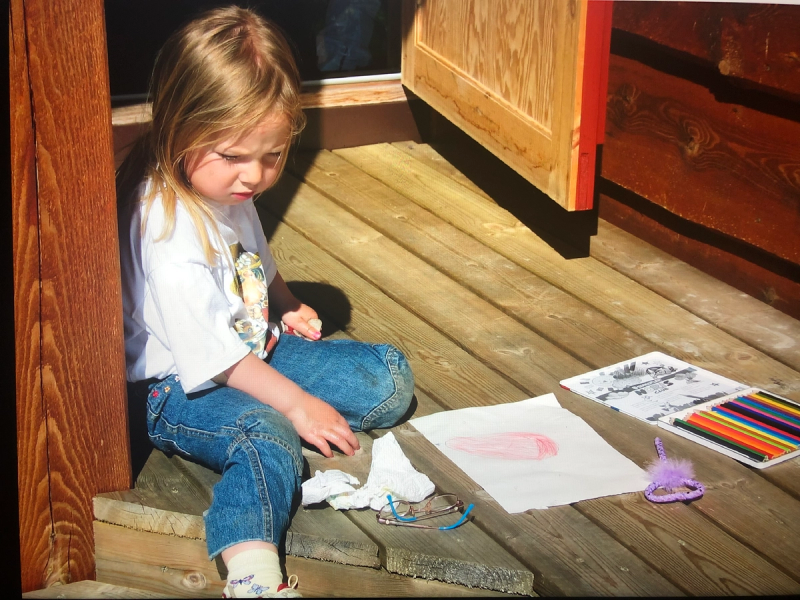 Meg, ca. 6 år, som sitter ute på sommeren og tegner på plattingen.