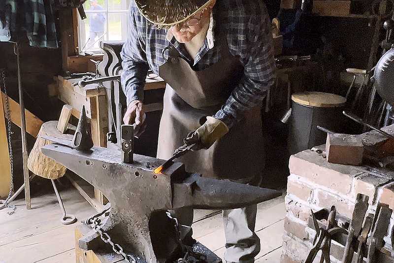 Blacksmith working a piece of iron on the anvil. 