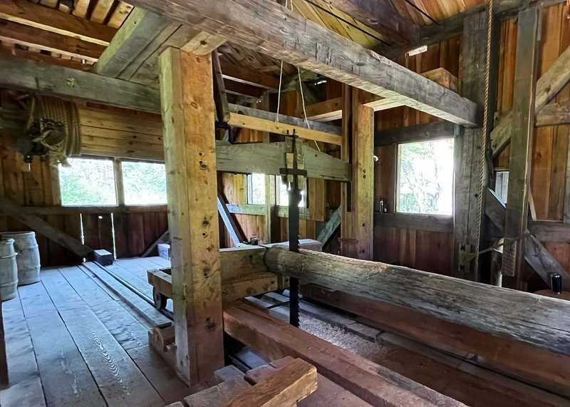 Interior of Leonard's Mill showing a up-and-down saw cutting through a log.