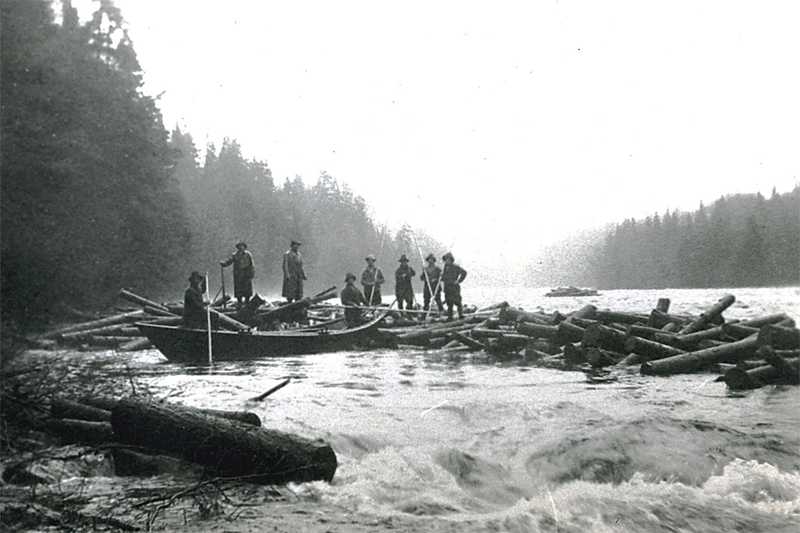 Eight men working on a small jam of logs. Two men holding bateaux in current on the Allagash/St. John Rivers.
