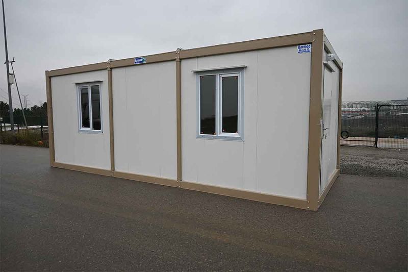 Standard white and beige container unit photographed from a three-quarter angle on a paved yard.