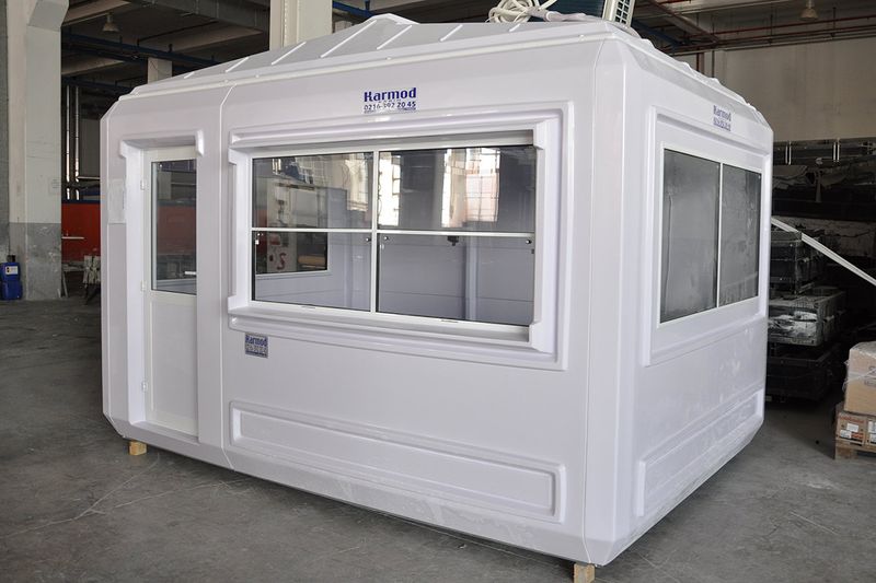 White GRP kiosk cabin with a full-width sliding service window, photographed inside the production facility before dispatch.