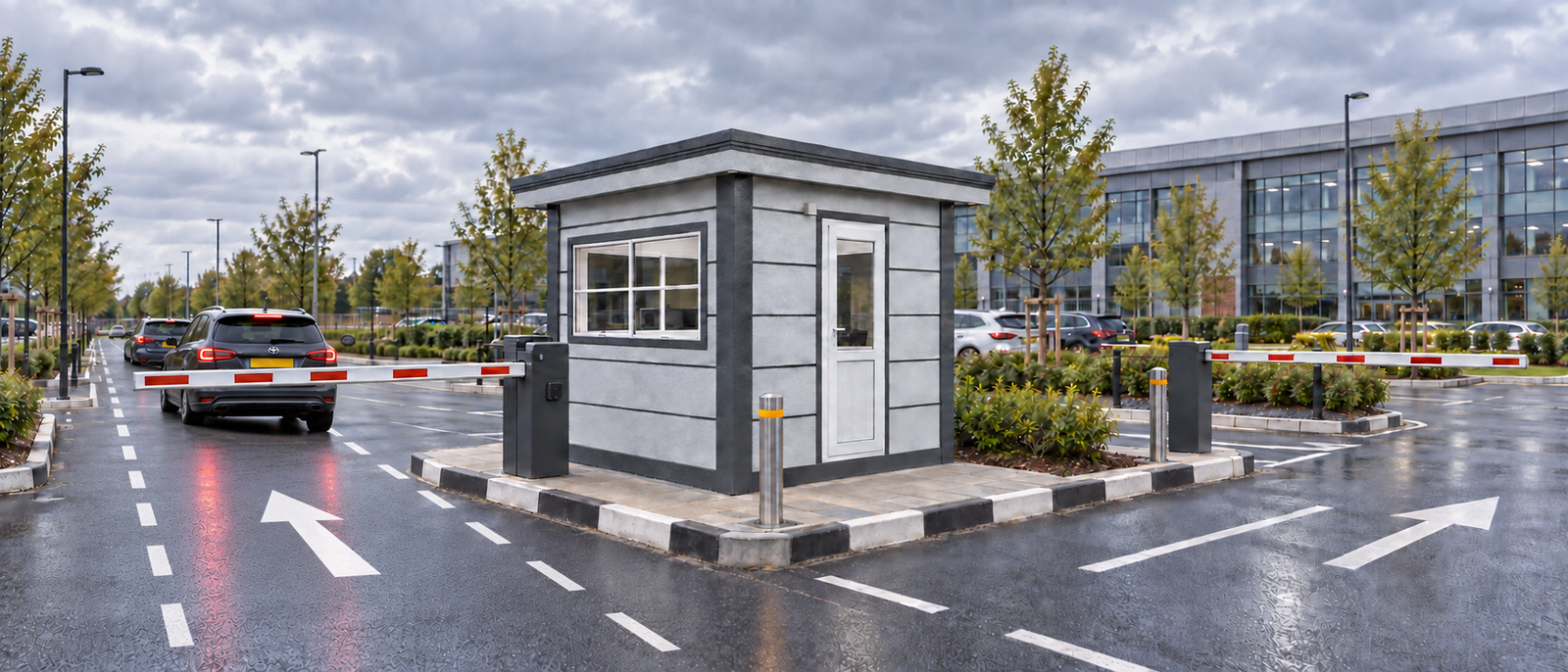 Car park attendant cabin between barrier arms on a kerbed island in a business park car park