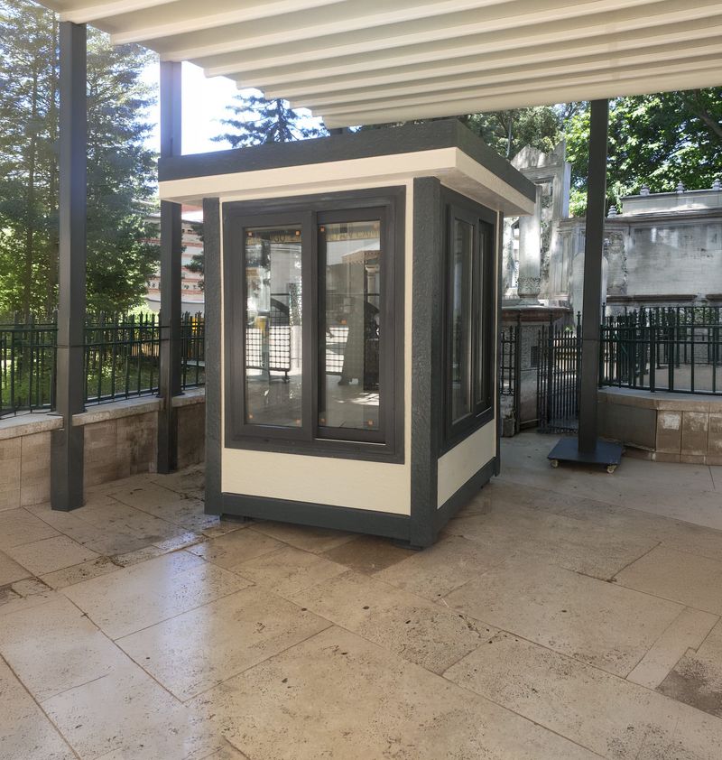Dark grey and cream Metro City cabin standing under a pergola canopy on travertine paving in a walled courtyard.