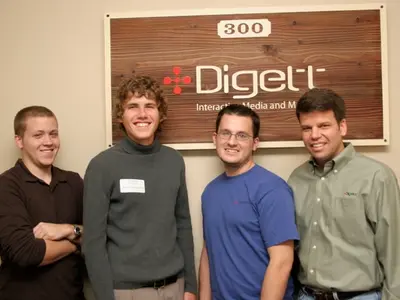 Four Digett team members posing by the office sign