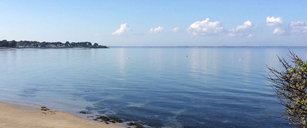 Baie de Quiberon au calme, plage de sable et eau miroitante sous un ciel bleu
