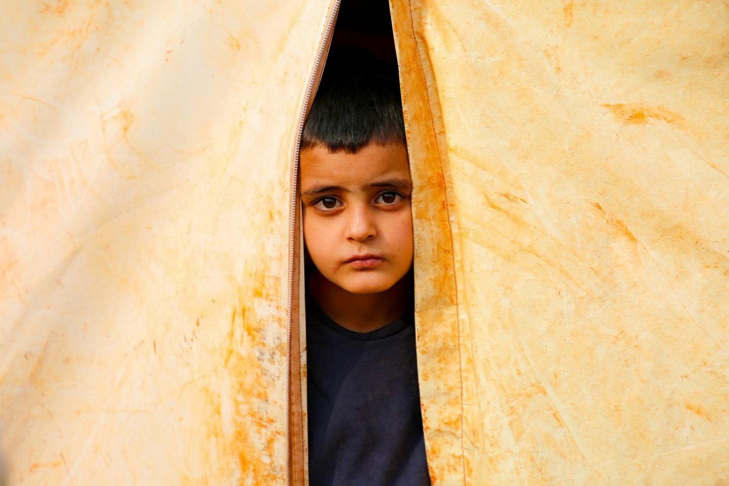 A boy in the Middle East peering out of his shelter