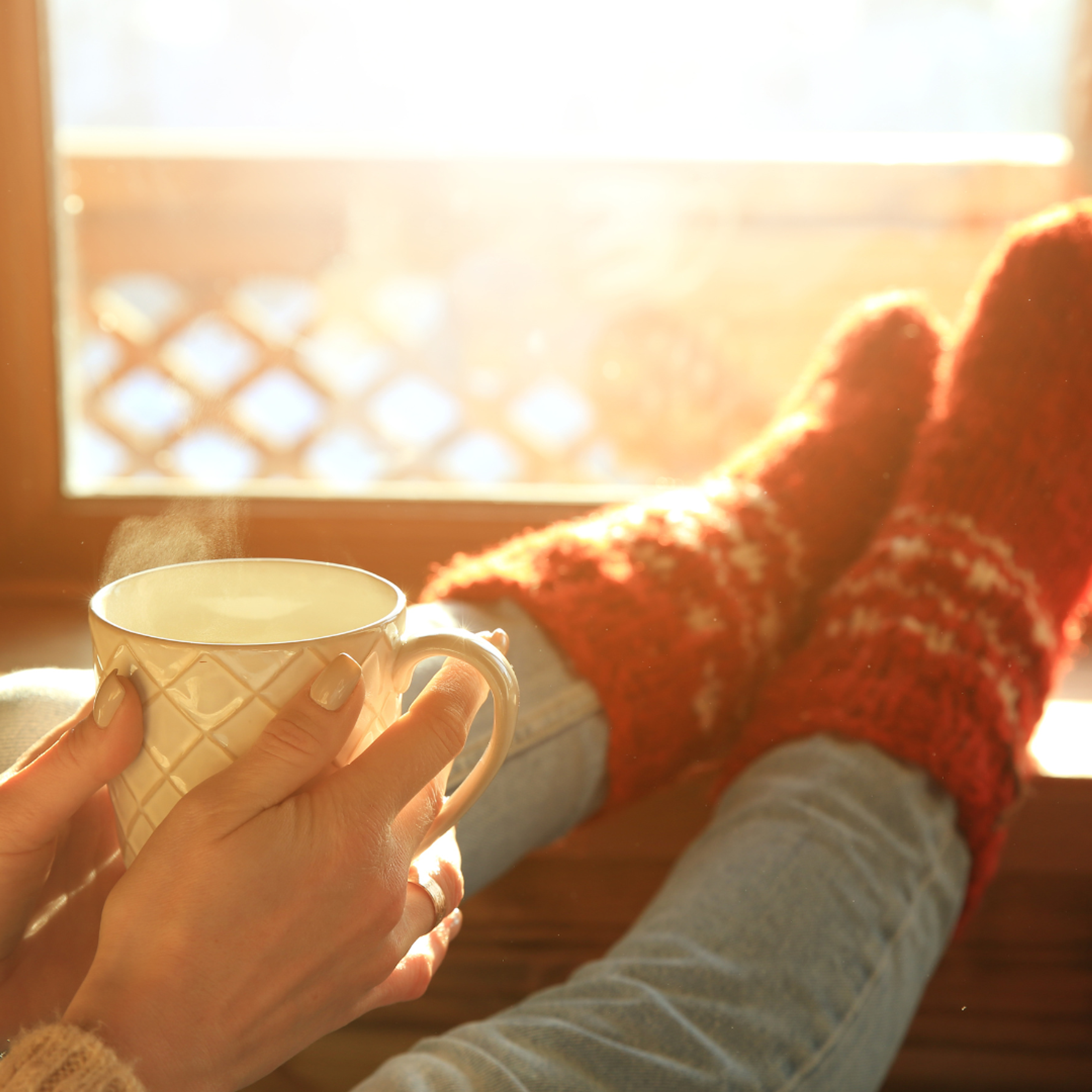 Fenêtre lumineuse, personne chaudement habillée avec tasse fumante