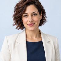Michele, travel virtual assistant, smiling with curly dark hair in a cream blazer